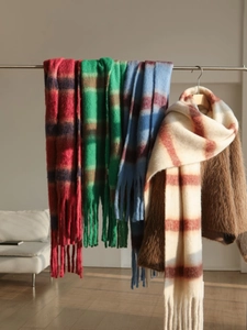 Detail view of colorful striped scarves with cozy bouclé texture and braided tassels