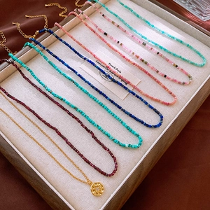 Detailed shot of multi-color gemstone beaded necklaces and gold pendant in jewelry tray