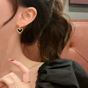 Vintage heart hoop earring with gold frame and black center shown on a model