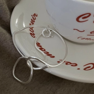 Minimalist S925 sterling silver snake chain bracelet with round spring clasp on a ceramic dish
