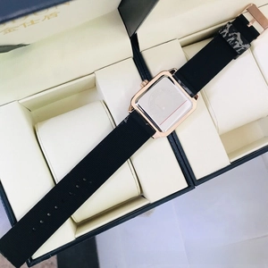 Detail view of square quartz watch with rose gold case and black silicone strap in box