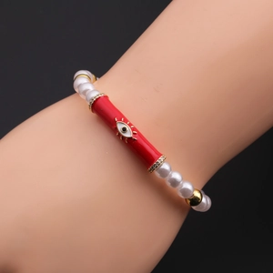 Detail of red evil eye charm bracelet with white beads on model's wrist against black background