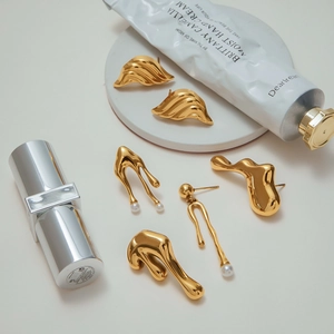 Detailed shot of golden liquid metal earrings with pearls and modern aesthetic design