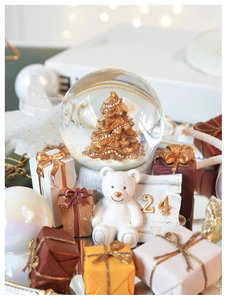 Macro detail of Christmas snow globe with golden tree and bear sculpture base