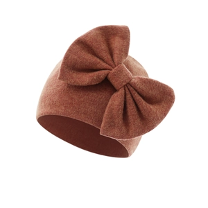 Detail of warm brown knit baby hat featuring a large decorative bow and soft texture