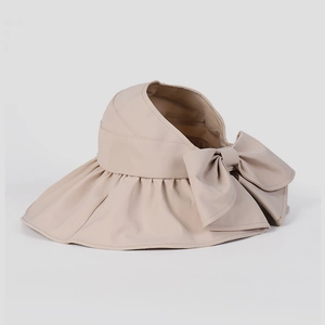 Dettaglio di visiera beige con tesa larga, fiocco decorativo e design aperto traspirante