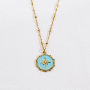 Detailed close-up of a gold starburst medal necklace with blue enamel and crystal