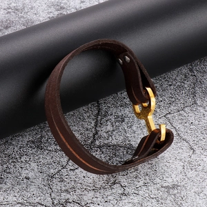 Detail of dark brown leather braided bracelet with gold pig nose anchor clasp design