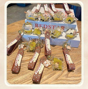Detail view of liquid bubble tea bear keychains with pearls and brown PVC hand straps