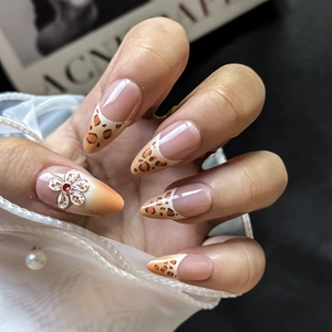 Detail of long almond nails with 3D white flower, red gem, and leopard print art