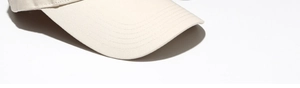 Detail of reinforced stitching on the brim of a cream-colored cotton twill baseball cap