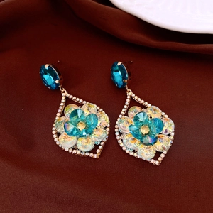 Detailed macro view of vintage gold earrings with blue floral crystals and small diamonds