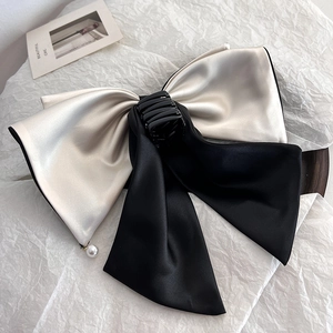 Detail of elegant black and cream satin bow hair claw clip with a delicate pearl charm