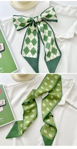 Close-up of green and white geometric pattern silk scarf tied on a white shirt collar