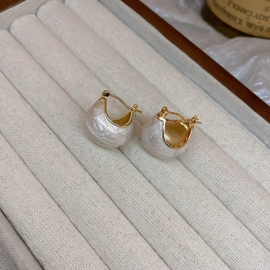 Vue macro de boucles d'oreilles dorées avec perles dans un écrin à bijoux en velours
