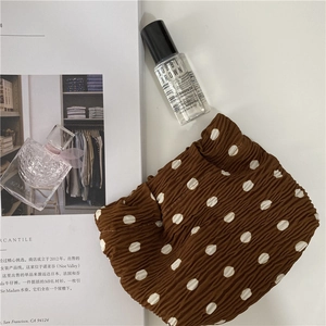 Detailed close-up of coffee brown pleated polka dot makeup bag with white dots