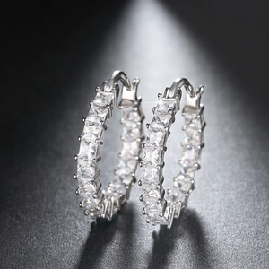 Macro detail of silver hoop earrings with square-cut cubic zirconia in prong setting