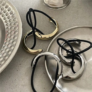 Detail of mirror-finish gold and silver semi-circle hair ties with black elastic bands