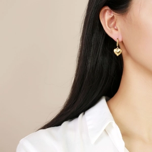 Golden heart-shaped hoop earrings modeled on female ear for a professional elegant look