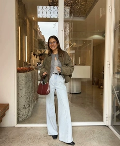 Scatto street style di una giacca scamosciata verde militare con jeans larghi blu chiaro