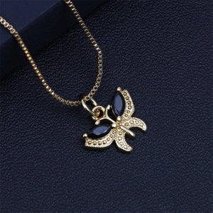 Close-up of golden butterfly pendant with black oval crystals and textured gold chain