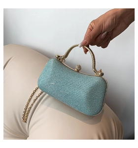 Detail of light blue glitter clutch bag with golden handle and pearl clasp detail
