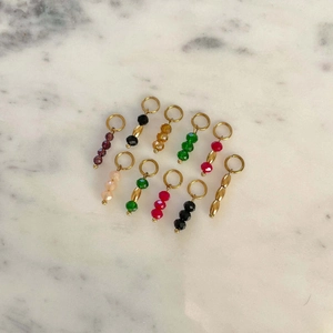 Detailed set of nine colorful crystal bead pendants with golden rings on marble background