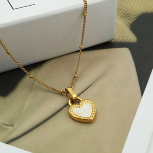 Macro detail of 18K gold plated heart pendant with white shell inlay and beaded chain