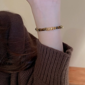 Macro detail of faux tiger eye stone beaded bracelet on wrist with gold accents