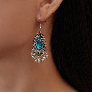Detail of bohemian silver tassel earrings with marquise blue stone on a female model