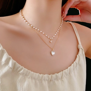Gros plan d'un collier double épaisseur avec perles et pendentif cœur doré sur mannequin
