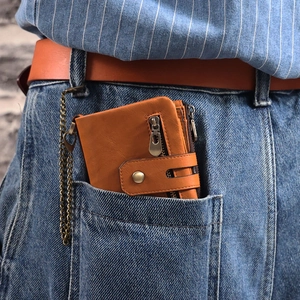 Vintage brown leather wallet with metal chain tucked in blue denim jeans pocket