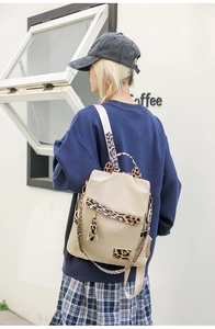 Detail of beige Oxford backpack with leopard print straps and tassel on model