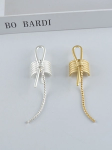 Detailed view of gold and silver knot earrings with dangling chains on a minimalist background