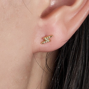 Minimalist gold lightning bolt earring with pavé zircon stones on a model ear