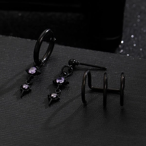 Macro shot of black gothic earrings set with purple gems and cross moon pendants