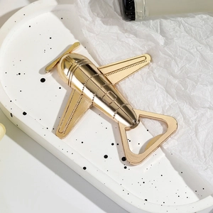 Elegant gold airplane shaped metal bottle opener on a professional white display tray