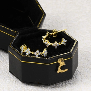 Detailed macro view of gold-plated flower stud earrings in a black velvet jewelry box