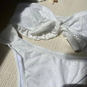 Detail of white eyelet embroidery bikini set with front knot and ruffle trim details