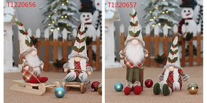 Christmas gnome dolls in red and green knit outfits on a sled in a snowy festive scene