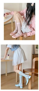 Detail shot of pastel velvet socks paired with Mary Jane shoes in a home setting