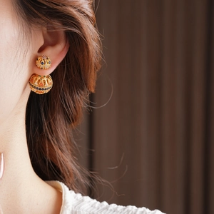Détail d'une boucle d'oreille vintage plaquée or 18k avec zircons colorés sur l'oreille
