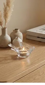 Detailed close-up of bird-shaped glass candle holder on wooden table with white tea light