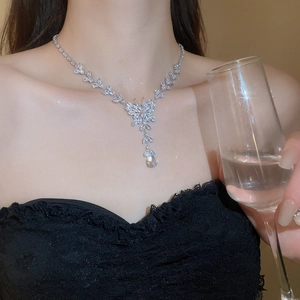 Silver butterfly necklace with zircon tassels and floral pendant worn by a model