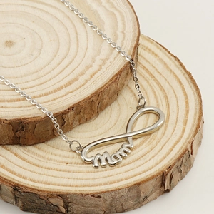 Collier MAMA en acier inoxydable argenté avec design infini sur un fond de tranche de bois
