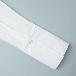 Detailed close-up of white textured shirt cuff with transparent button and clean stitching