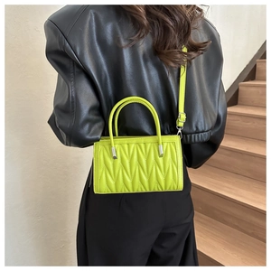 Close-up of lime green quilted handbag with silver hardware on a shoulder strap