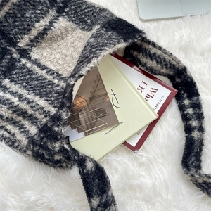 Detail of plush black and white checkered shoulder bag with soft wool-like texture