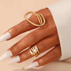 Detail of chunky gold irregular geometric rings worn on hand with white nails