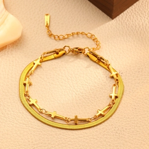 Détail du bracelet double couche en or avec chaîne serpent et pendentifs croix sur cuir